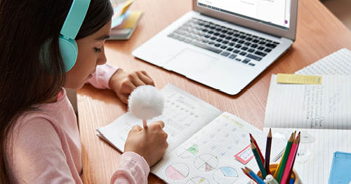 An online school student takes notes in a distraction-free home classroom.