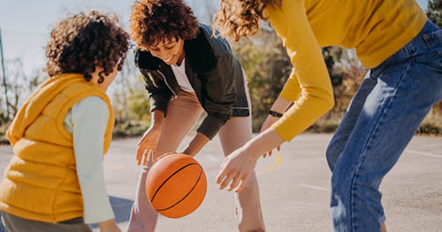 A family playing basketball as part of a summer hobby for teens. 